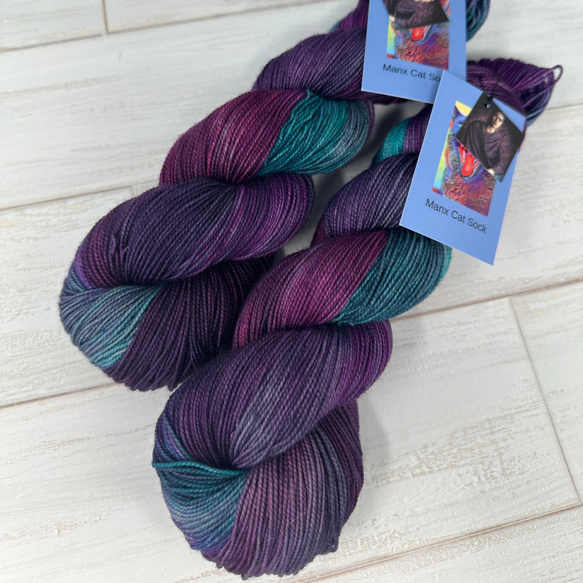 two skeins of Falkland sock yarn hand dyed by Laughing Cat Fibers in their Damas de Morado colorway