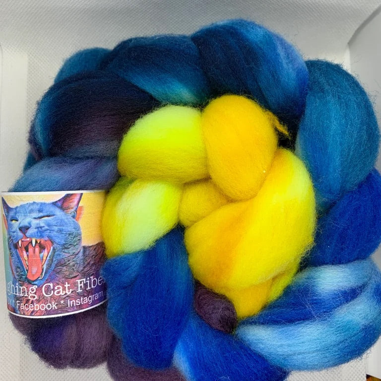 A bundle of dyed wool roving in shades of blue and yellow, with a label showing a starry night sky.