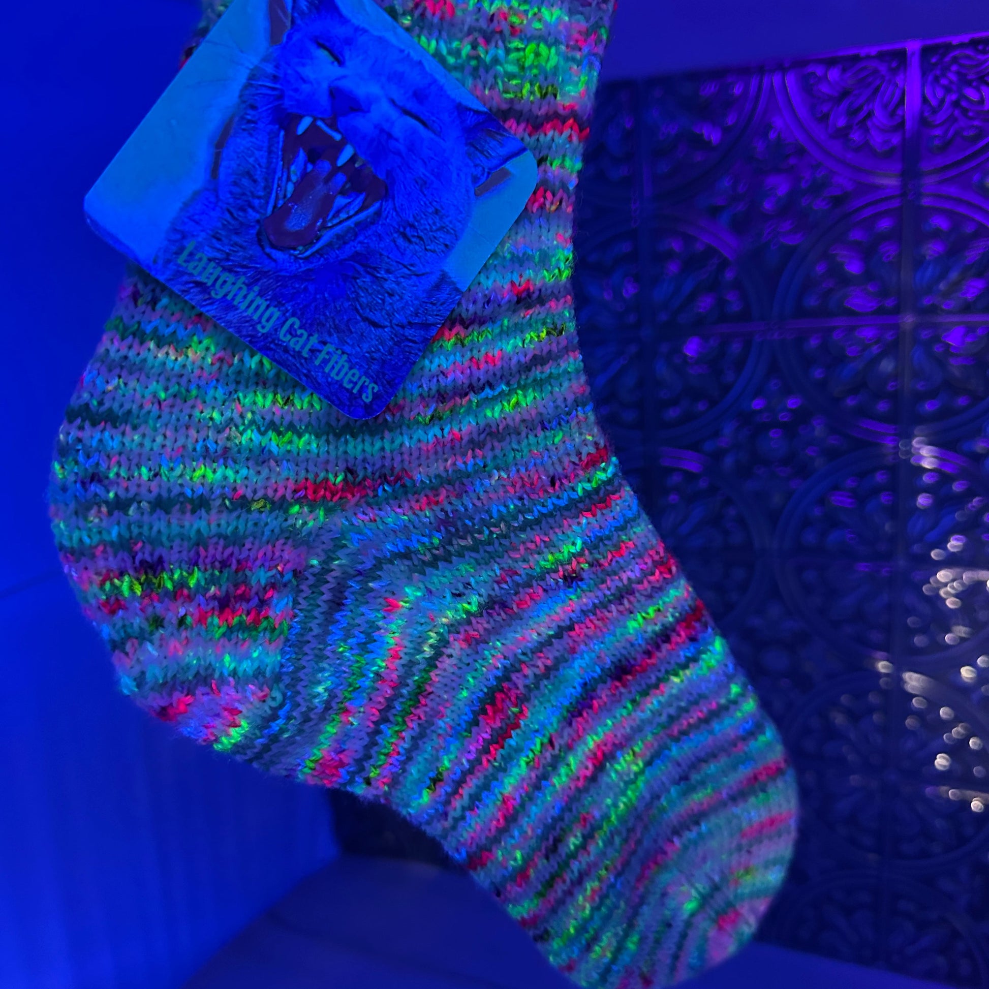 picture of a knit sock under black light yarn dyed by Laughing Cat Fibers 