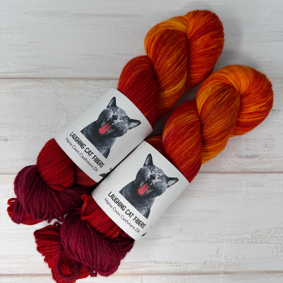 Two skeins of multicolored yarn with labels on a light wooden surface