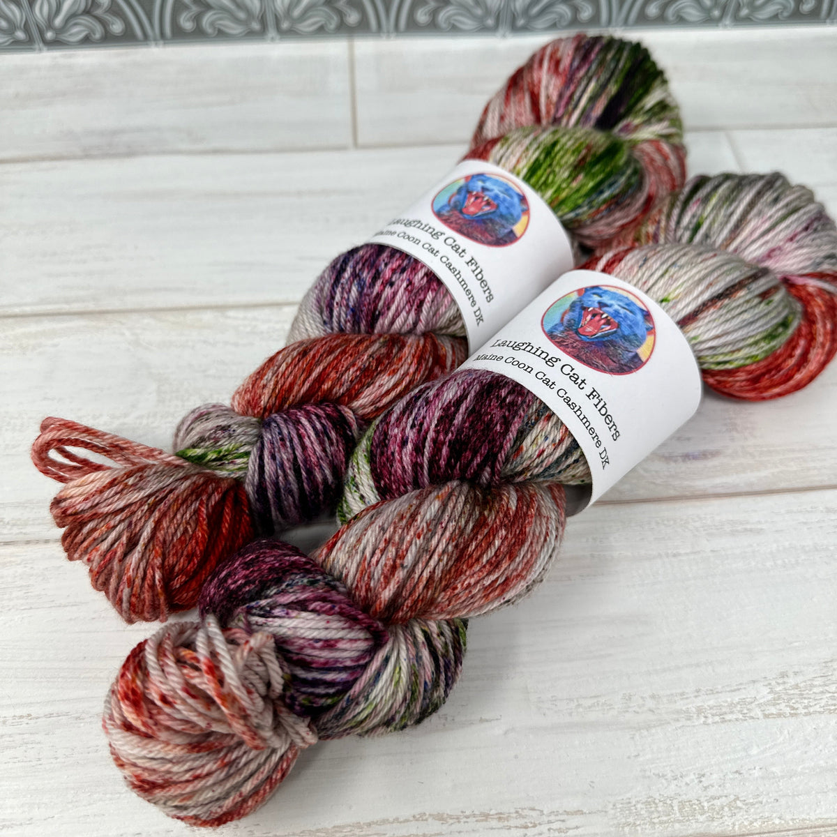 Three skeins of multicolored yarn with labels on a textured surface.