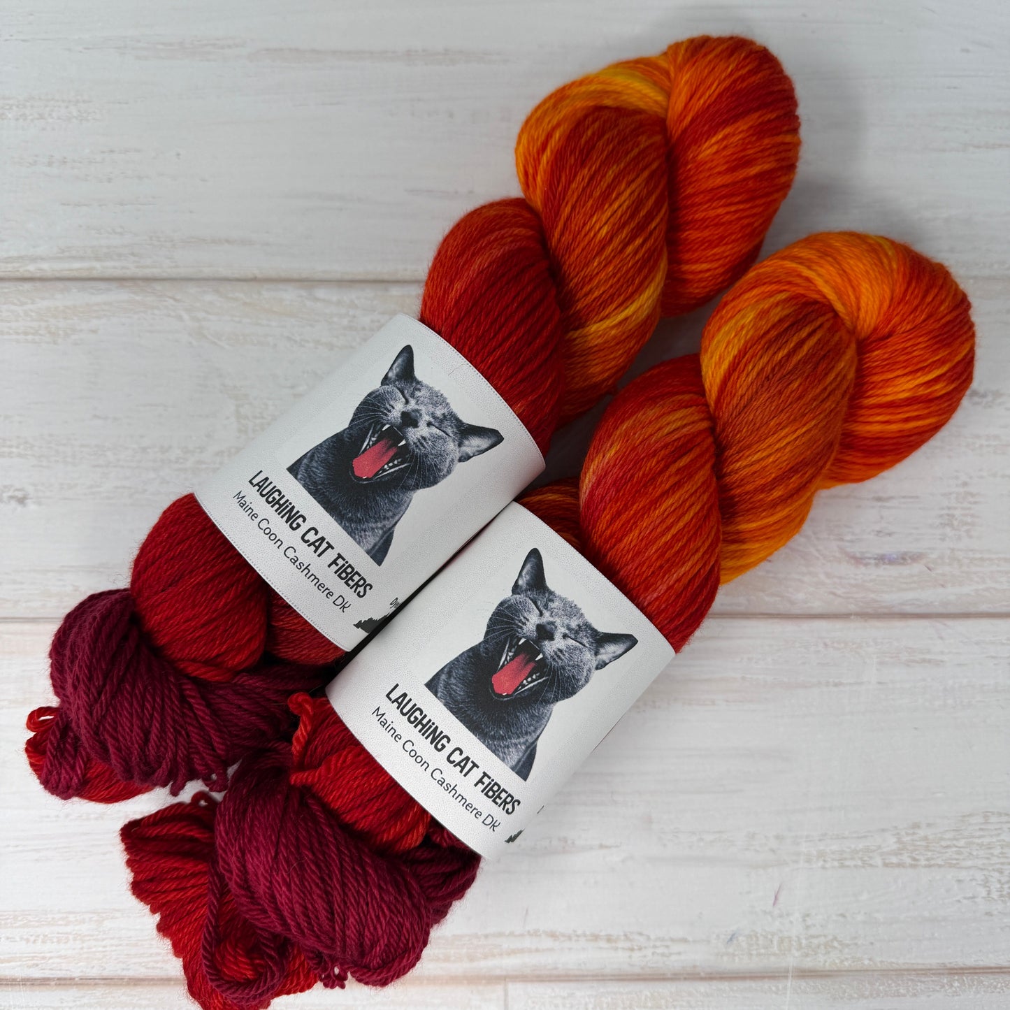 Two skeins of multicolored yarn with labels on a light wooden surface