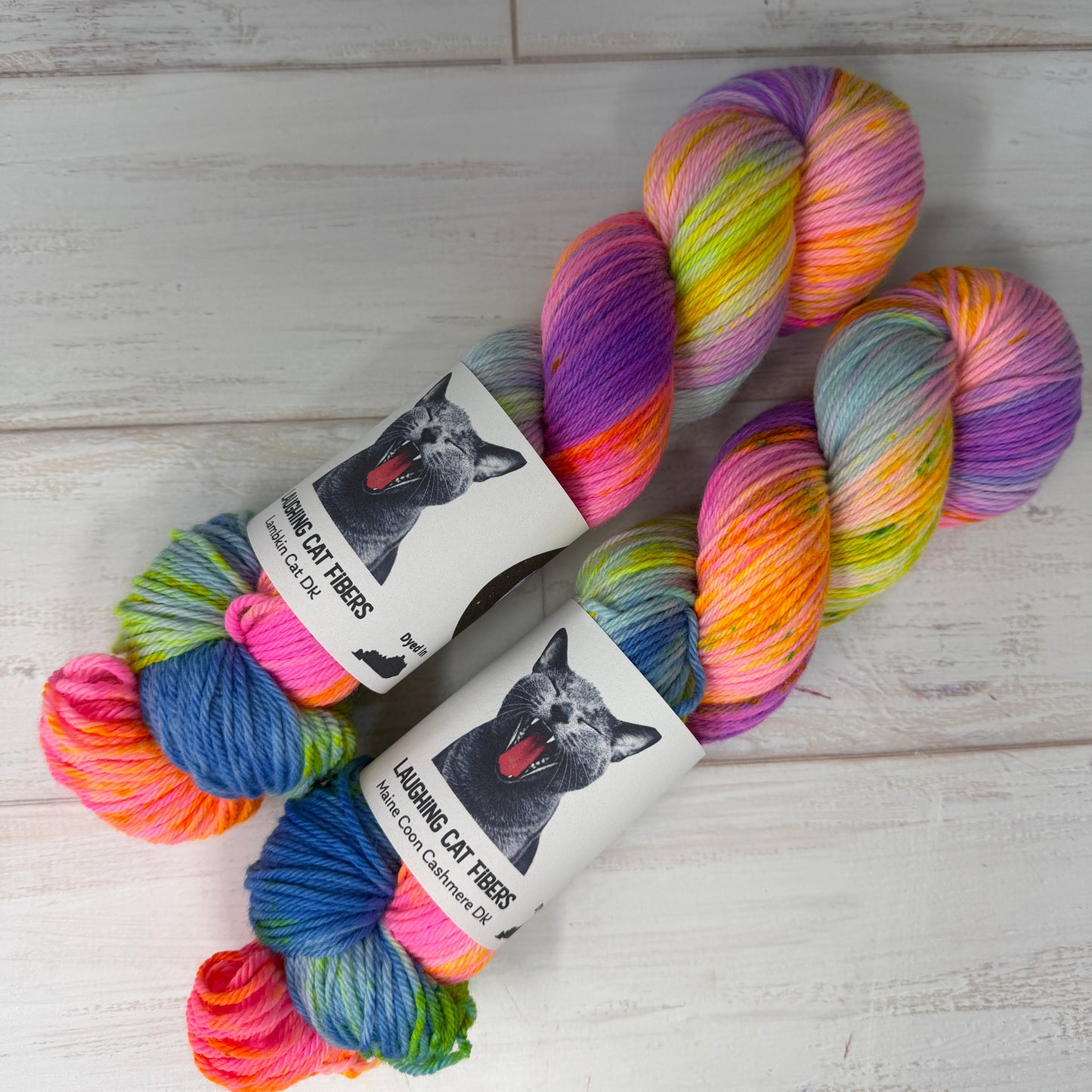 Two skeins of multicolored yarn with labels on a light wooden surface