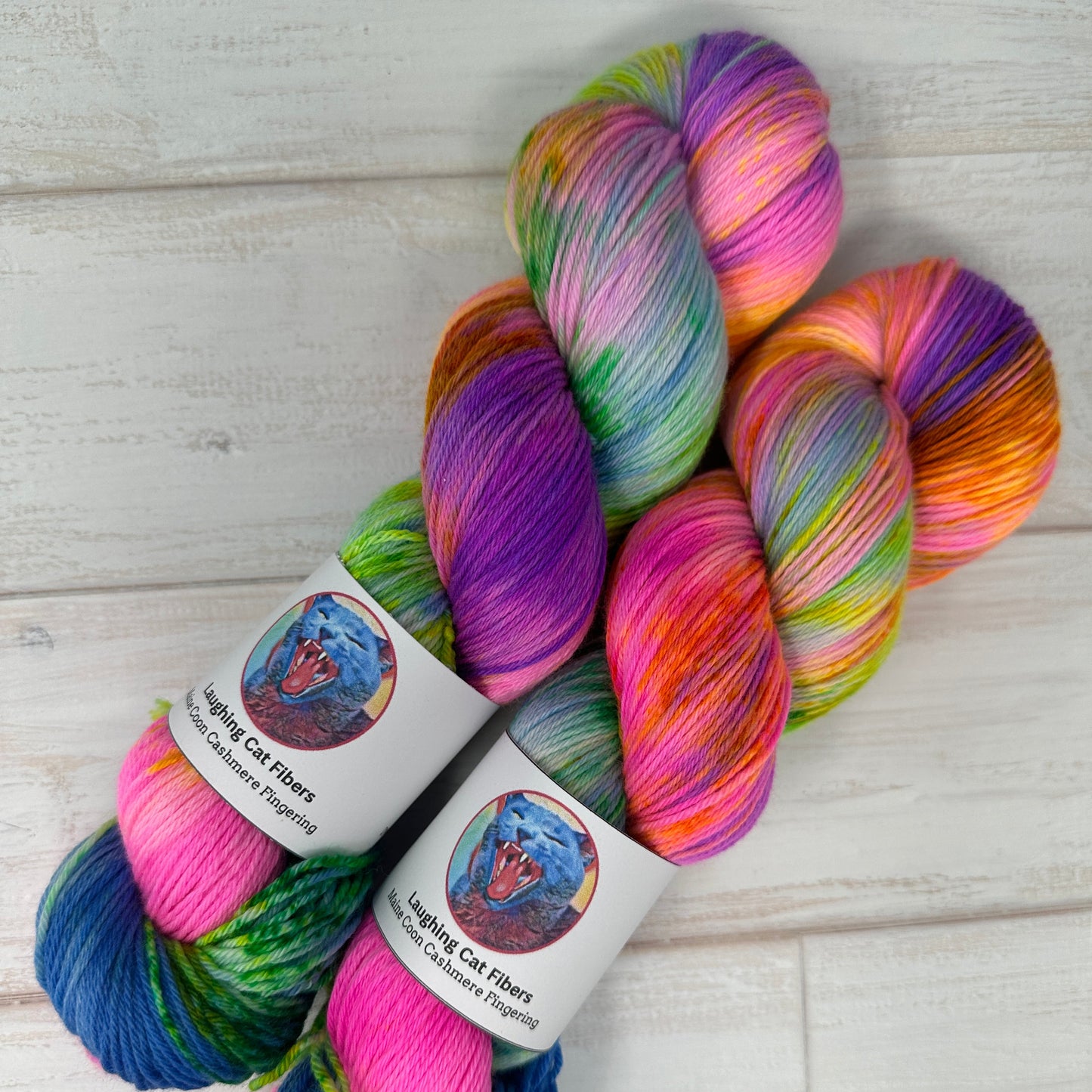 Colorful skein of yarn with two labeled skeins on a light wooden surface