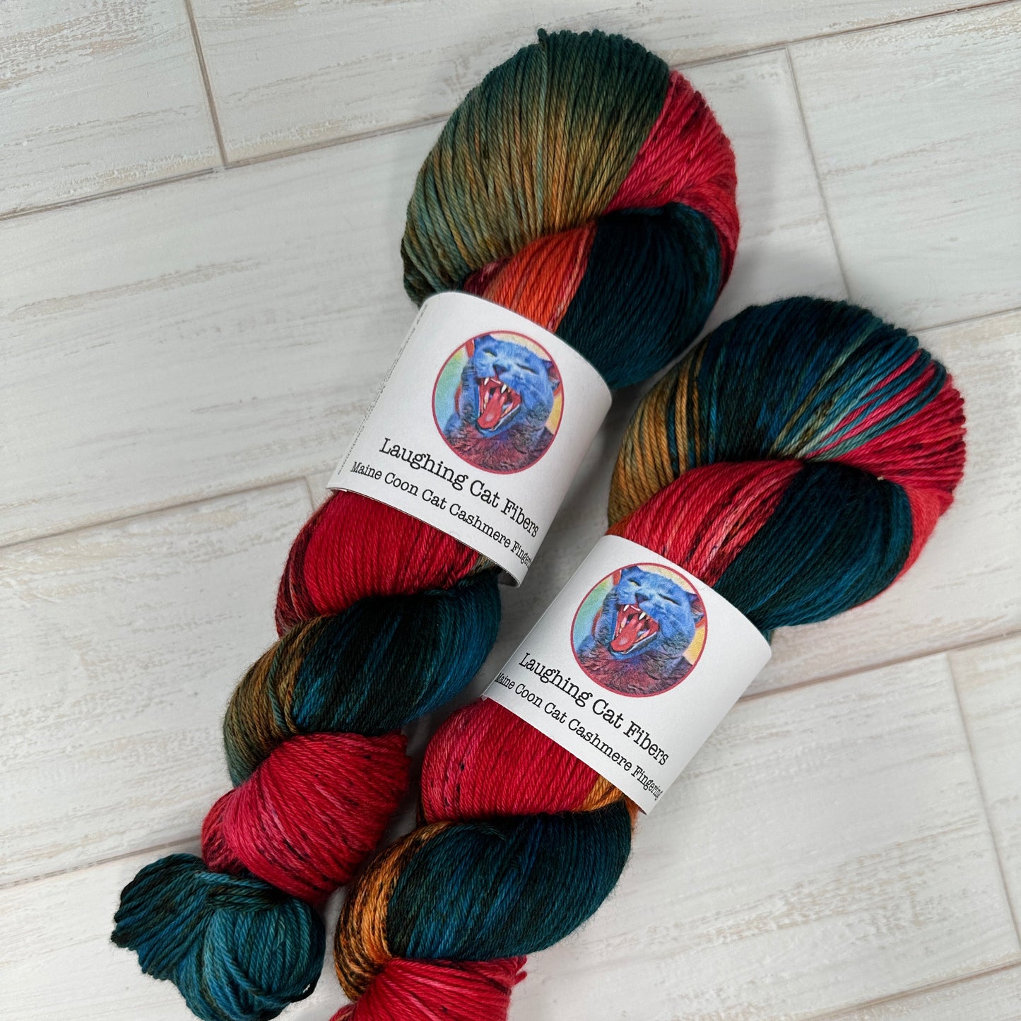 Two skeins of multicolored yarn on a white wooden surface.