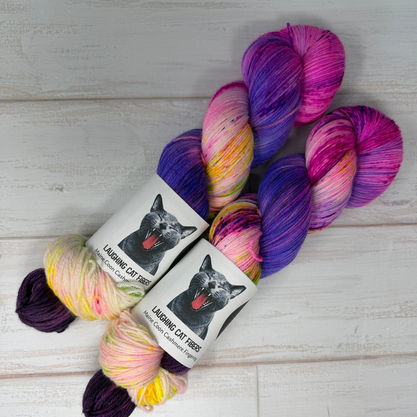 Multicolored yarn skeins with a label featuring a CAT on a light wooden background