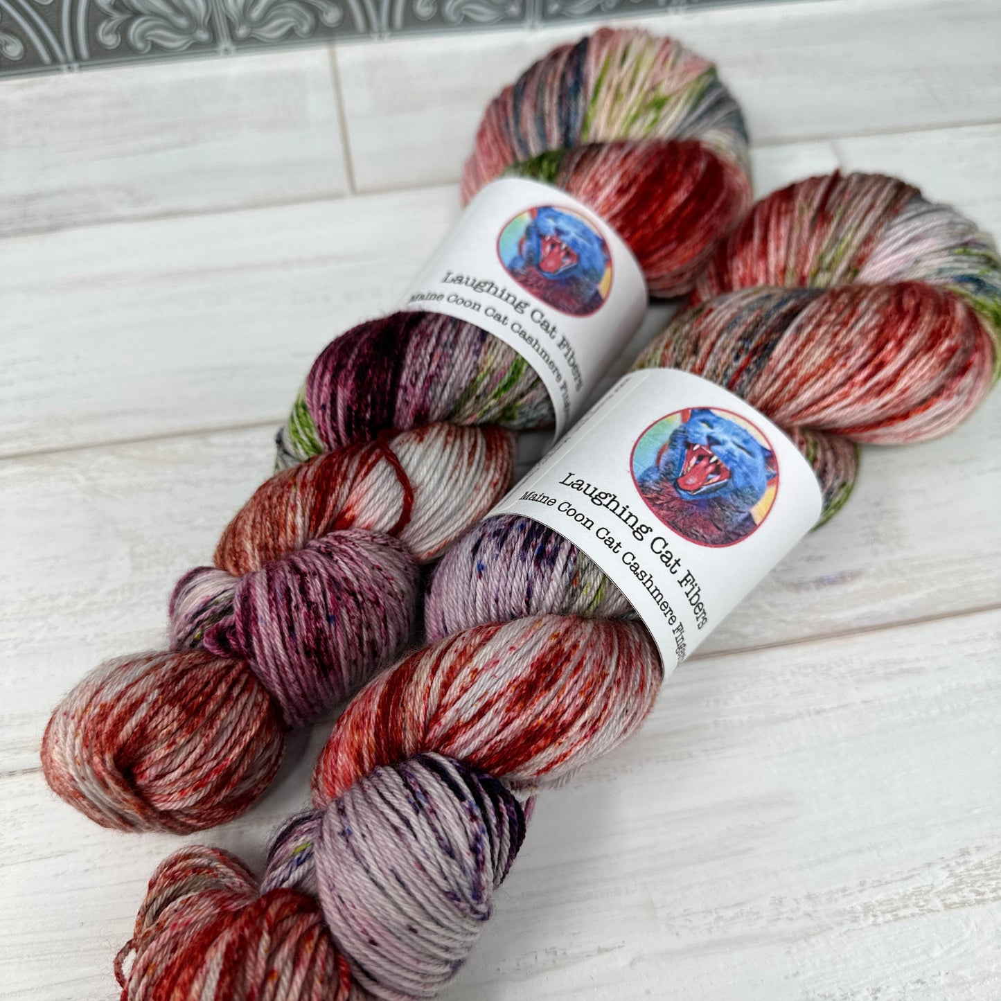 Three skeins of multicolored yarn with labels on a textured surface.