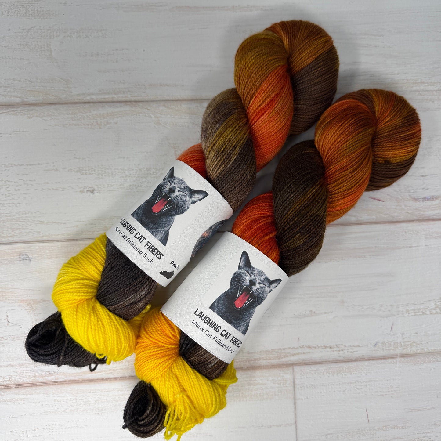 Three skeins of yarn with labels on a light wooden surface