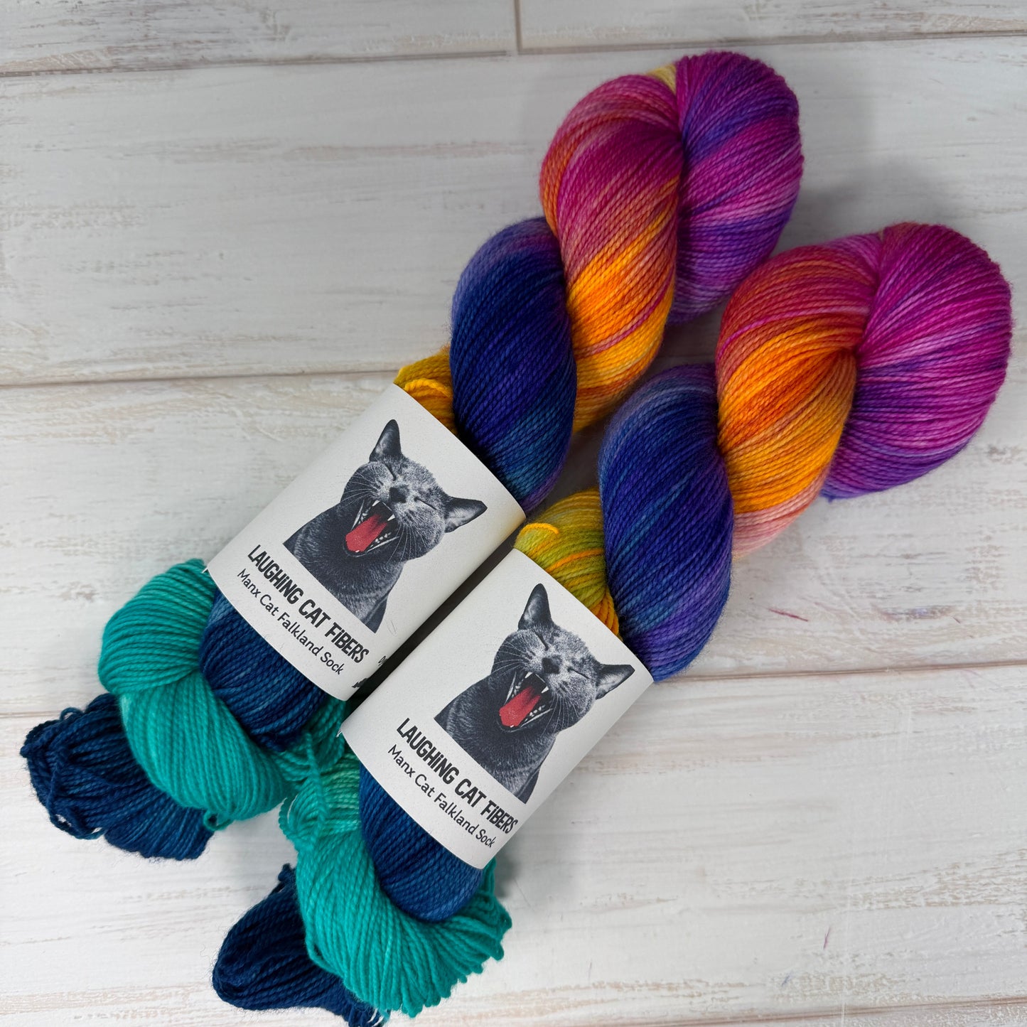 Colorful skein of yarn with 'Laughing Cat Yarns' labels on a wooden surface