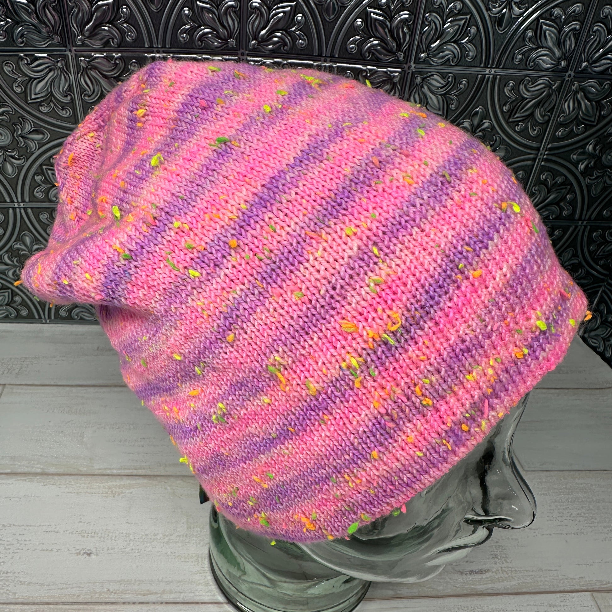 “Musselburgh Hat sample knit in pink and purple neon nep hand dyed yarn on ToyBob Sock base, shown in natural light.”