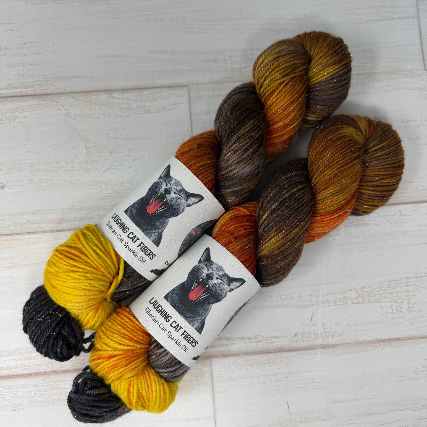 Three skeins of multicolored yarn with labels on a light wooden surface
