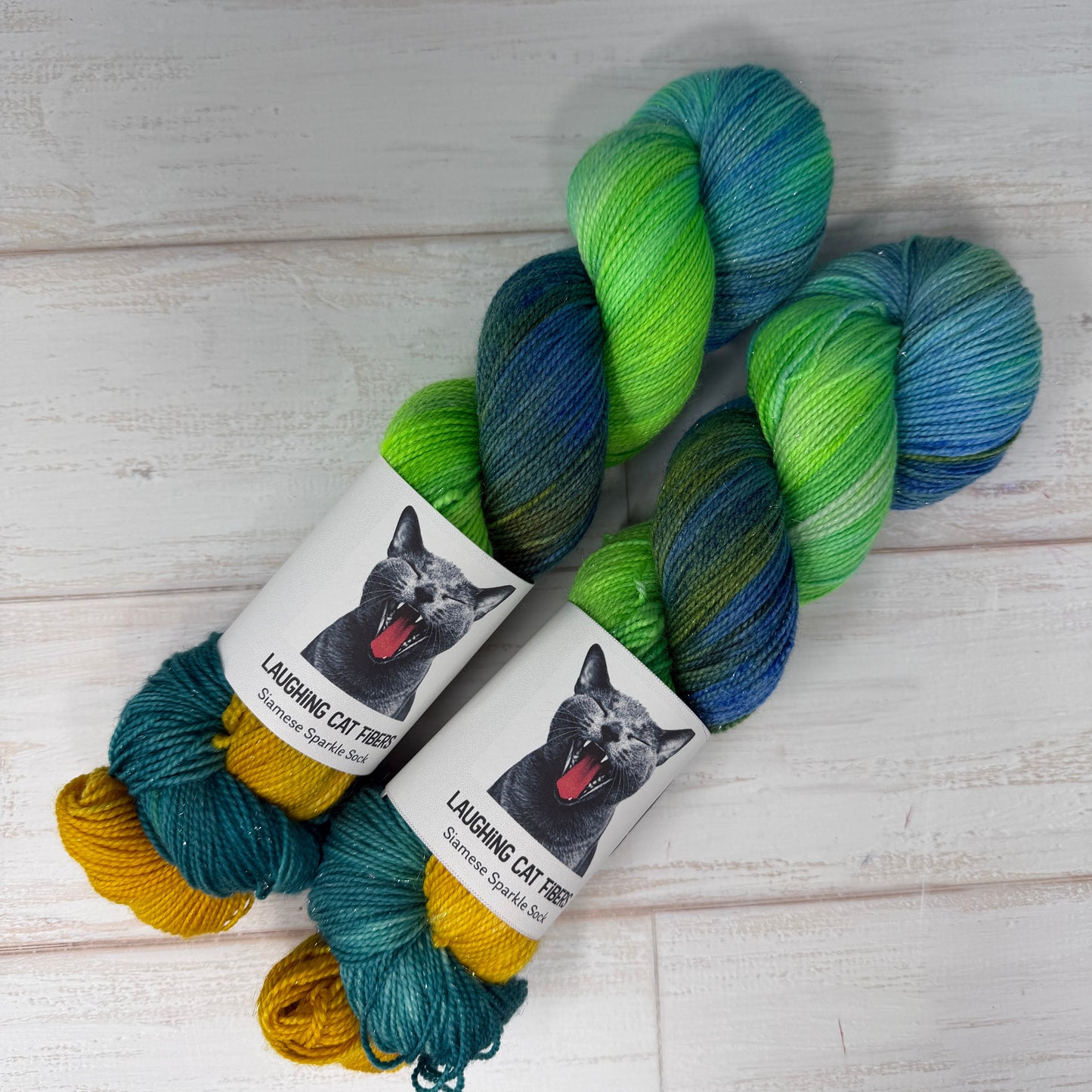 Two skeins of yarn with a label featuring a cat on a wooden surface