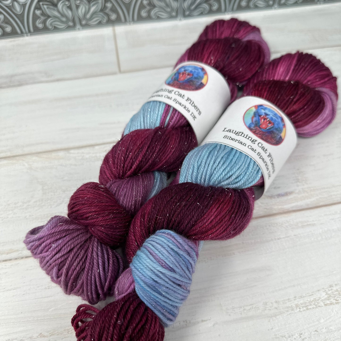 Two skeins of multicolored yarn on a textured surface.