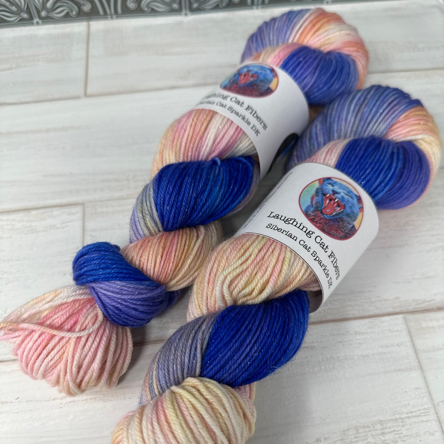 Two skeins of multicolored yarn with labels on a light wooden surface