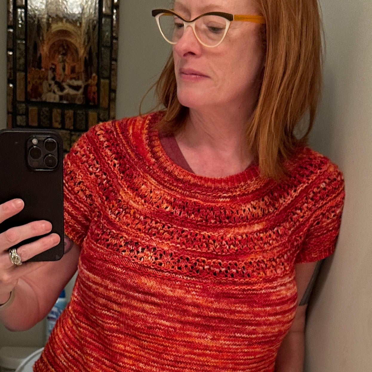 Person wearing a red sweater taking a mirror selfie.