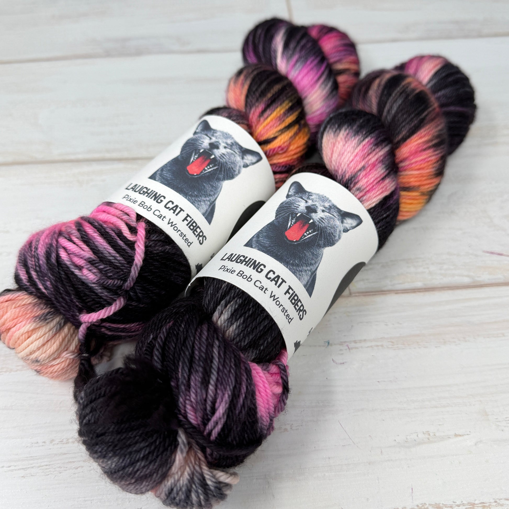 “Two skeins of The Poet X hand dyed yarn showing deep black overdyed layers with warm undertones.”