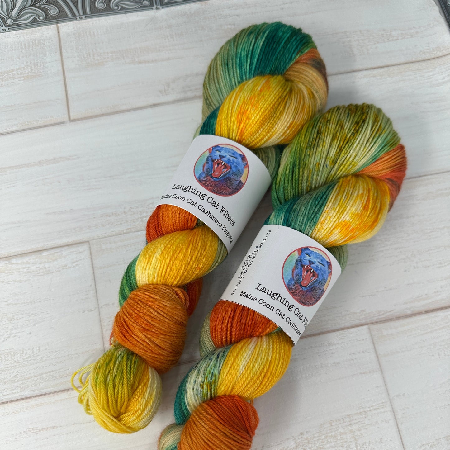 Two skeins of multicolored yarn with labels on a light wooden surface