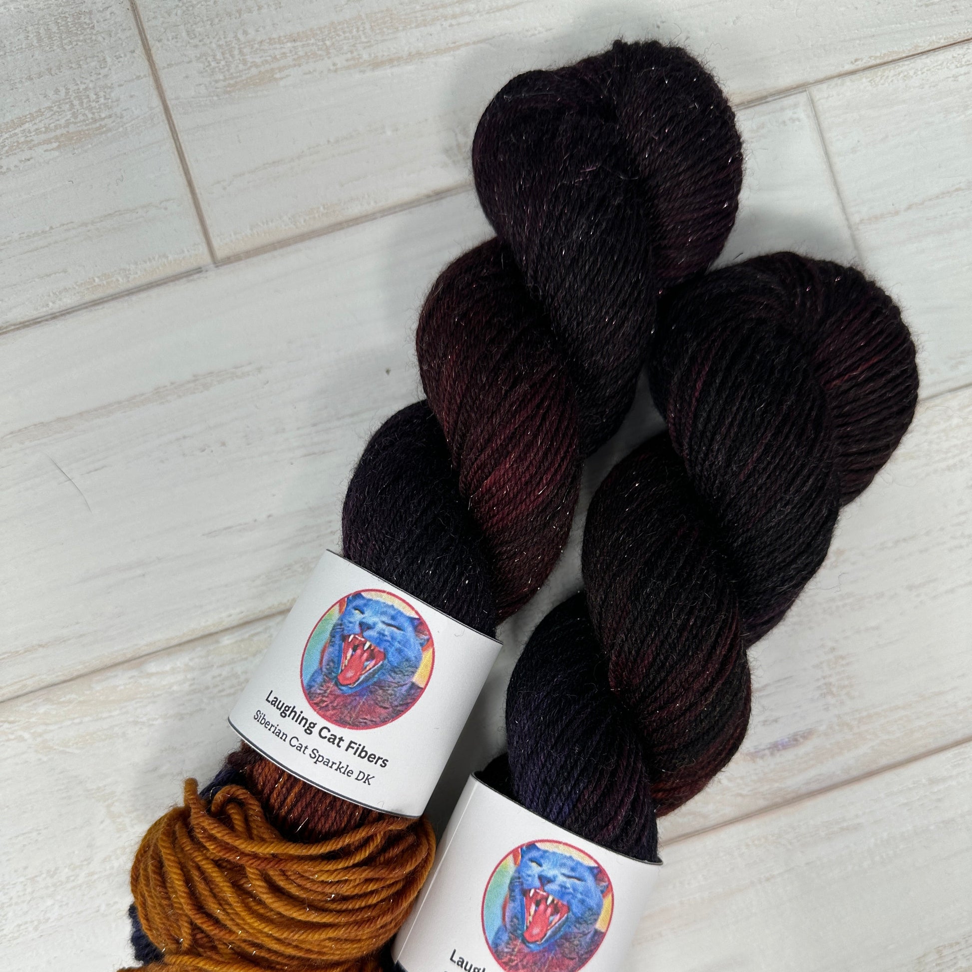 angle view of two skeins of hand dyed yarn by Laughing Cat Fibers in their colorway Judith