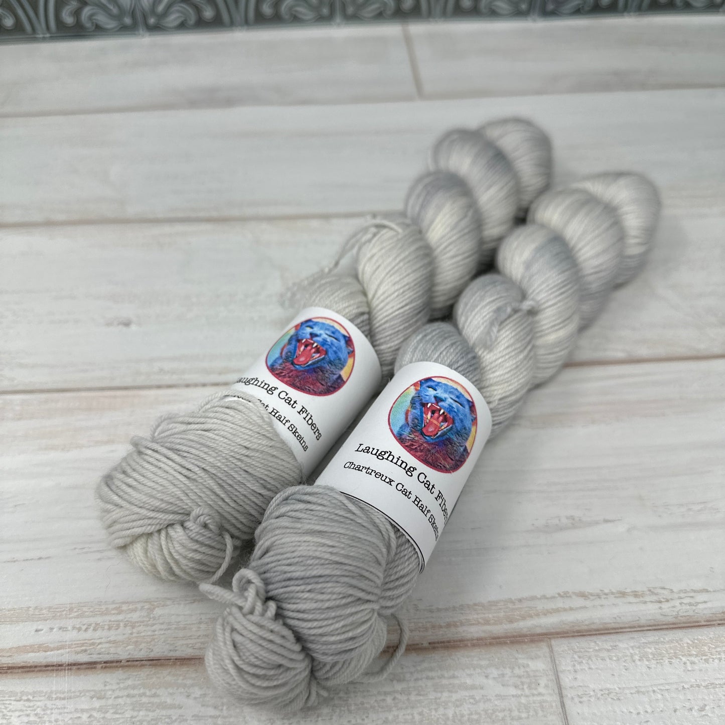 Two skeins of a gray tonal dyed by Laughing Cat Fibers in their Silver Gourd colorway 