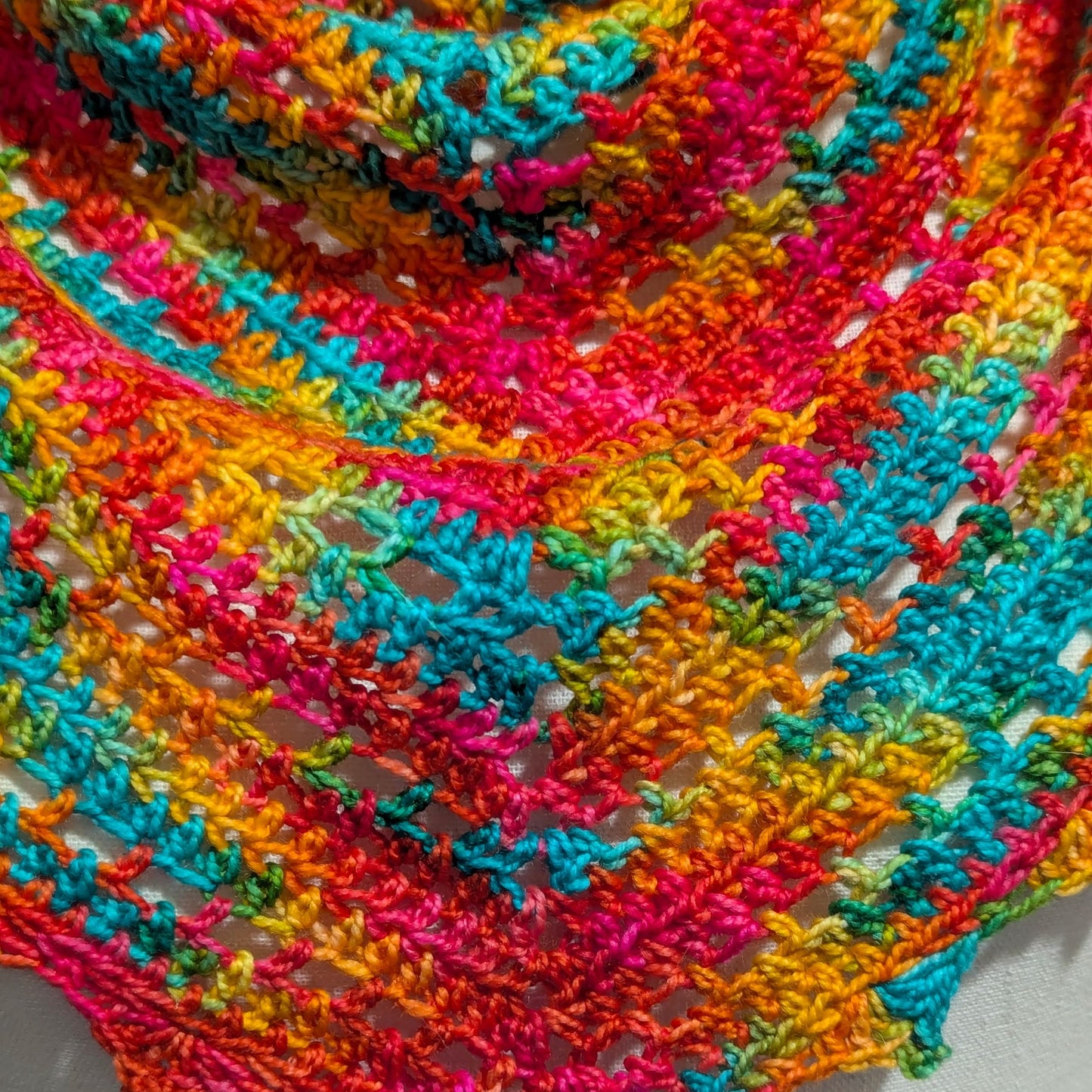 Close-up of a colorful crocheted shawl with vibrant patterns on a white background