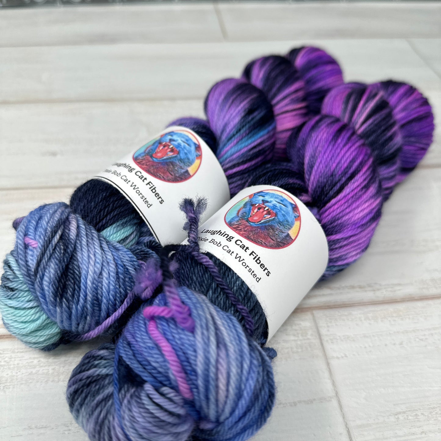 Two skeins of multicolored yarn with a label on a textured surface