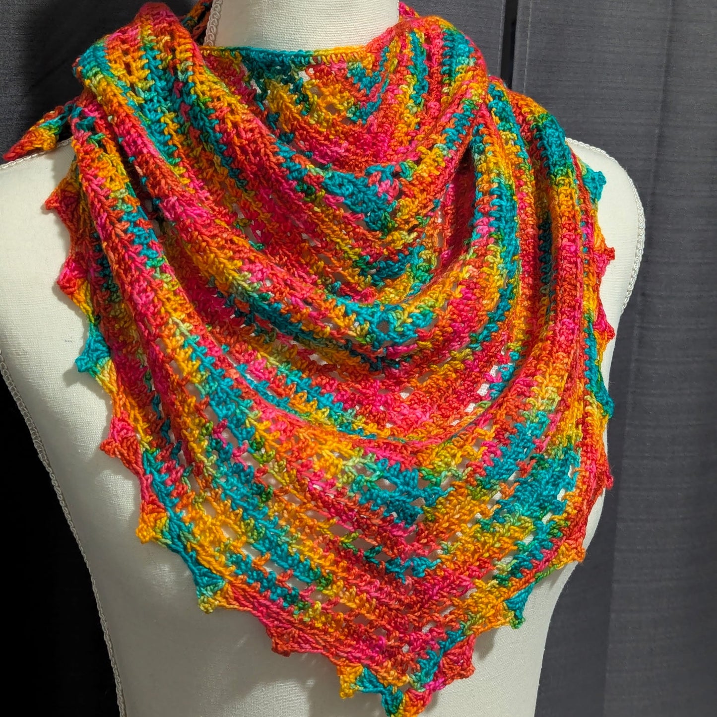 Colorful knitted shawl on a mannequin against a gray background