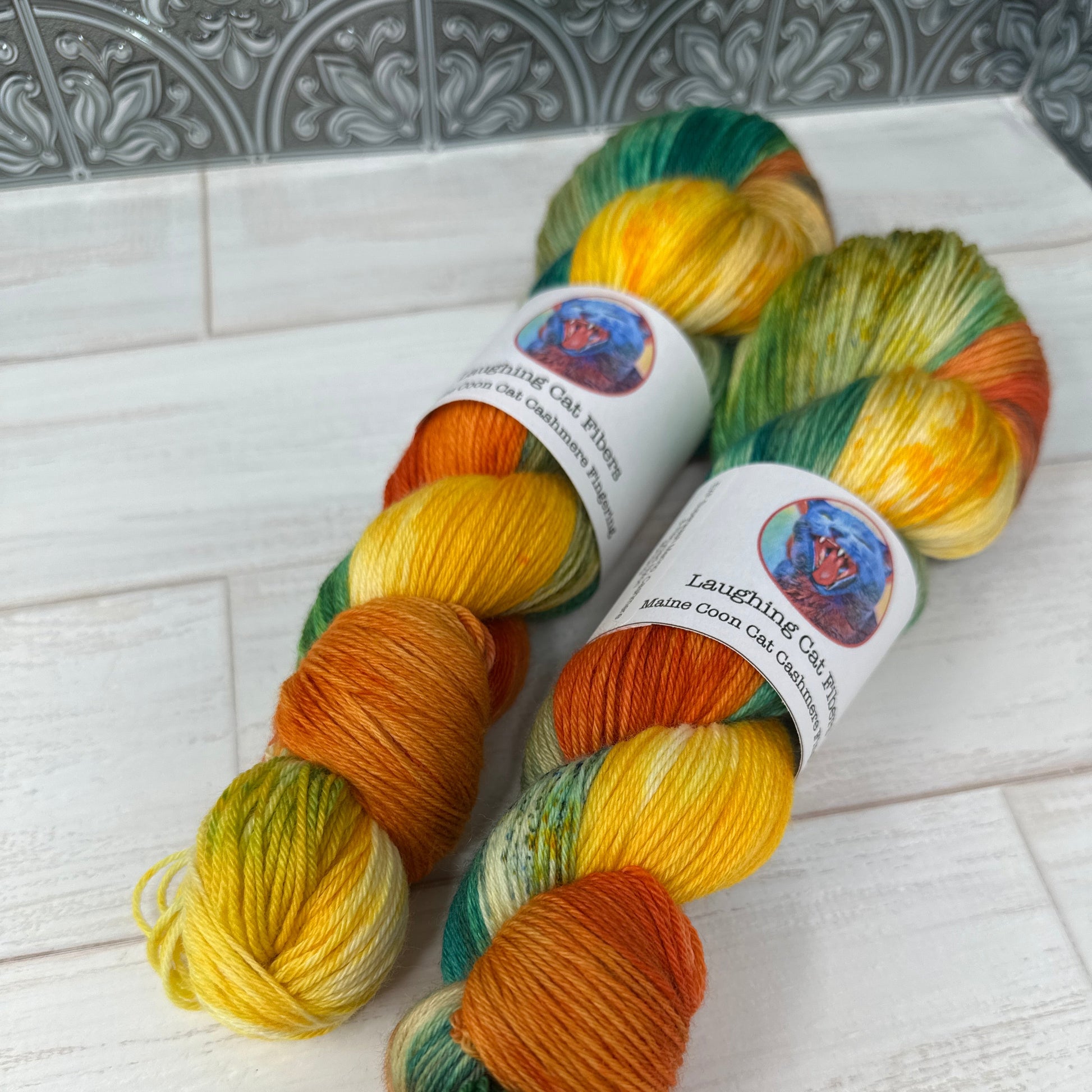 Three skeins of multicolored yarn with labels on a light wooden surface.