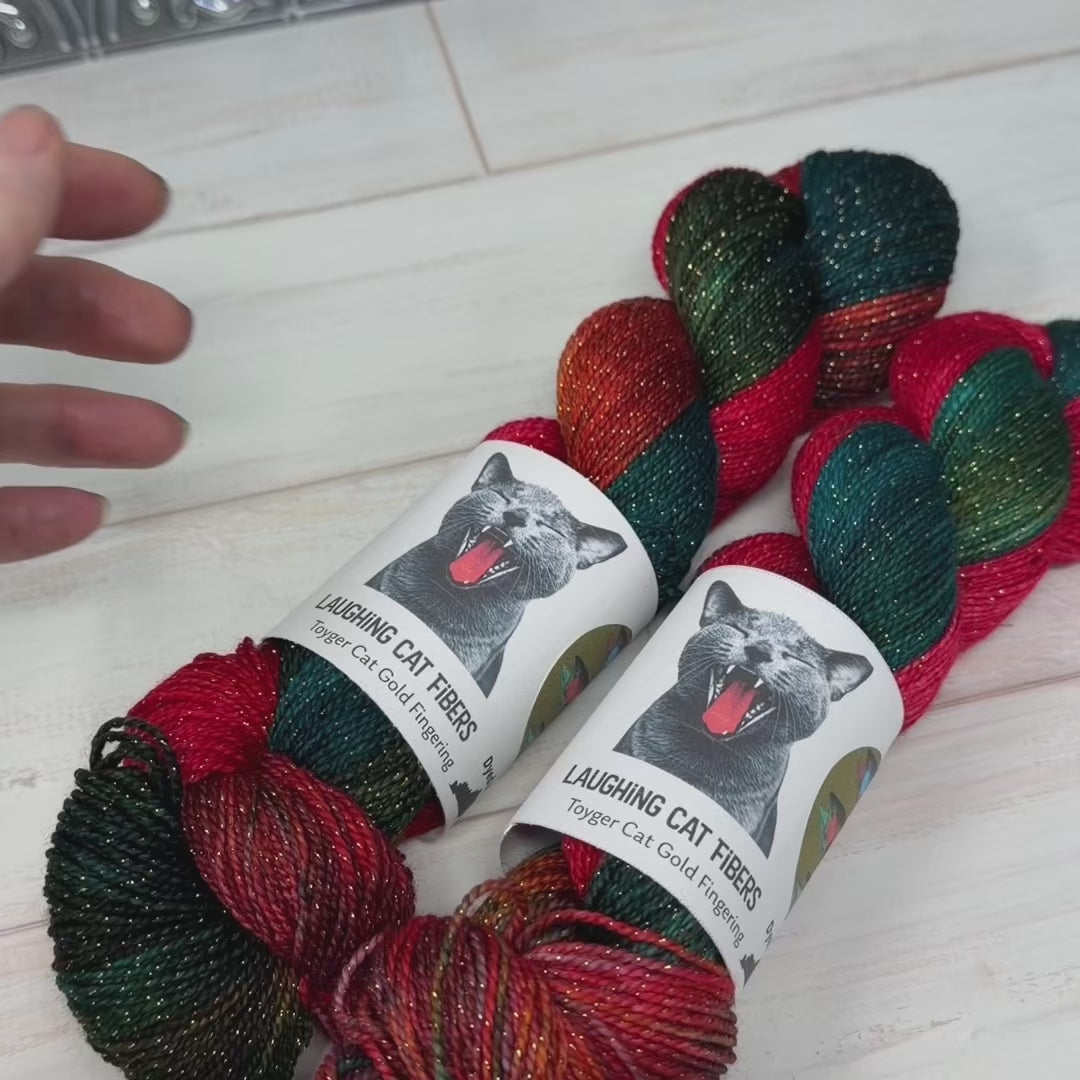 Load video: New Toyger Cat Gold Fingering base, featuring Salmon Run! Smooth and silky - you'd never know there was lurex twisted with the fiber. It creates an consistent sparkle throughout!
