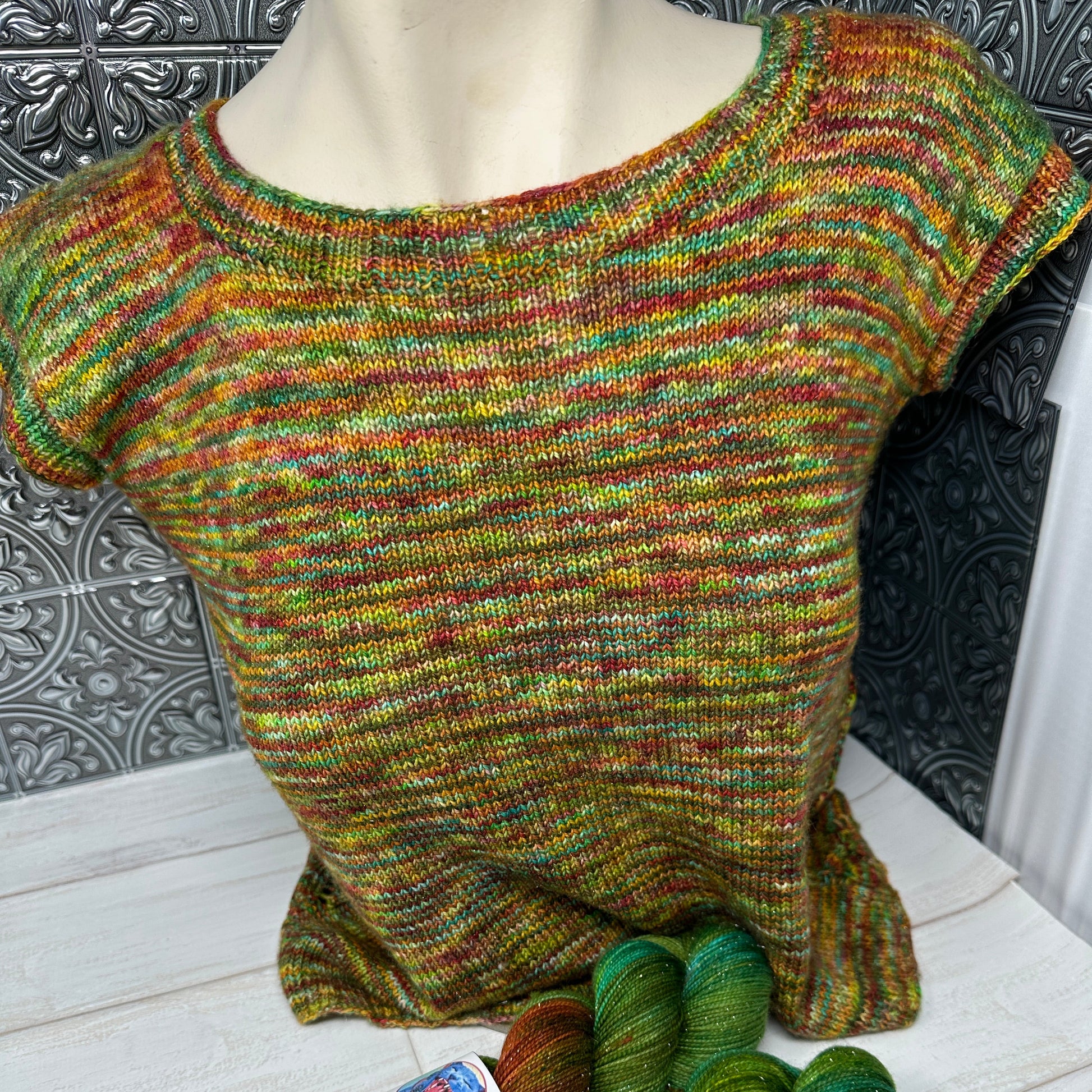 Knitted sweater and two skeins of yarn on a wooden floor