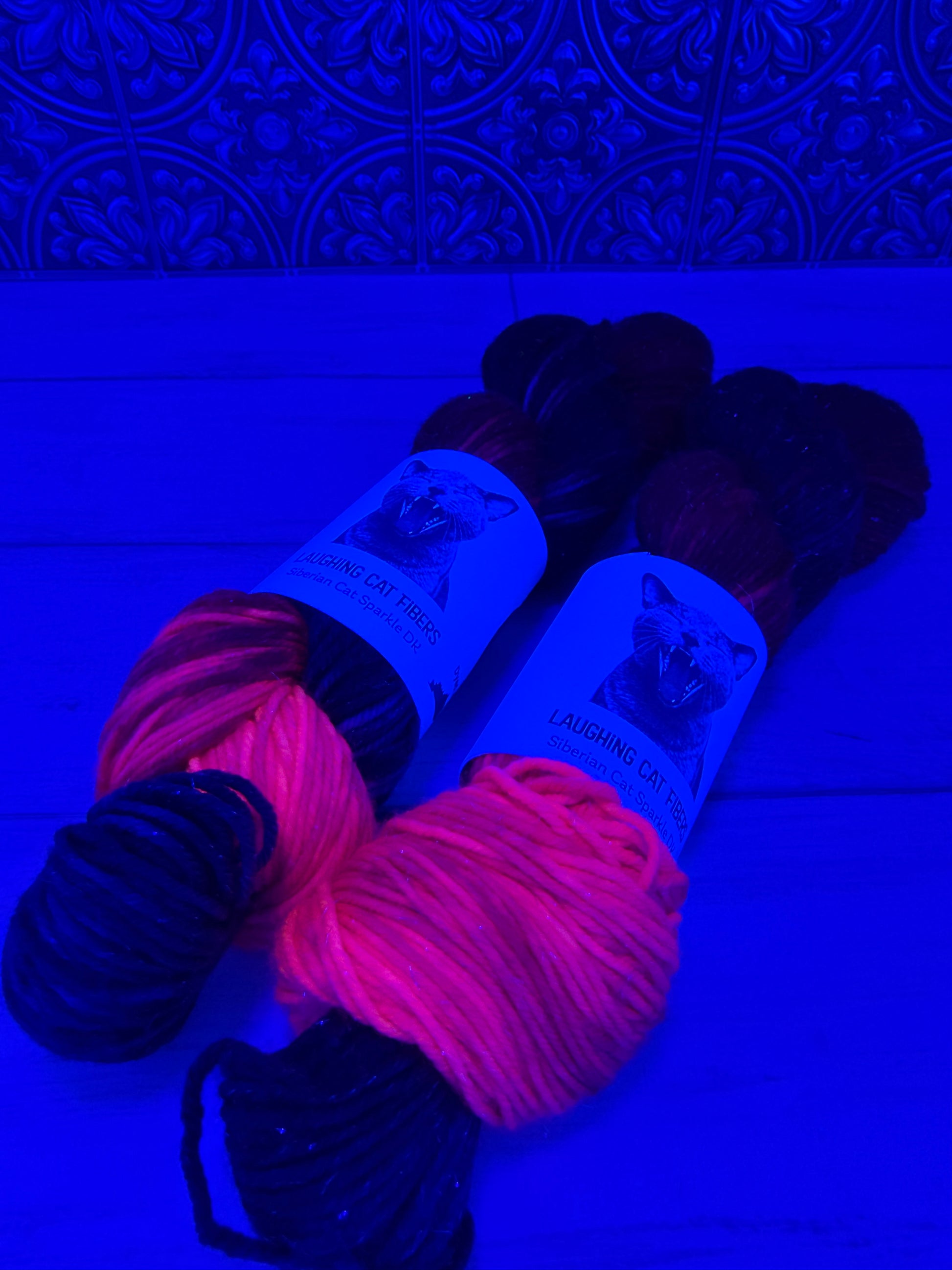 Two skeins of sparkle DK yarn, hand dyed in the Heart Nebula colorway under black light 