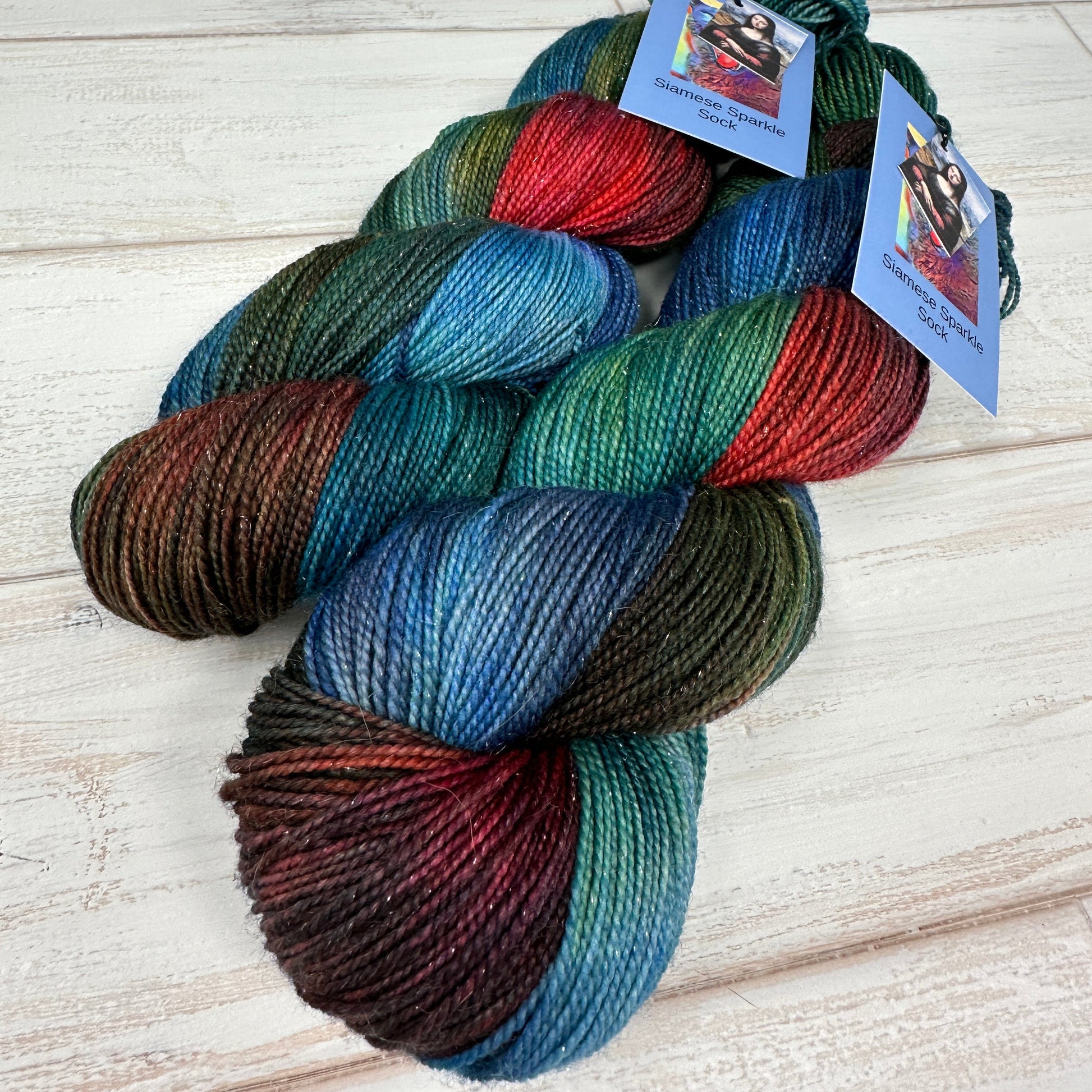 two skeins of sparkle sock yarn hand dyed by Laughing Cat Fibers in their Mona Lisa colorway