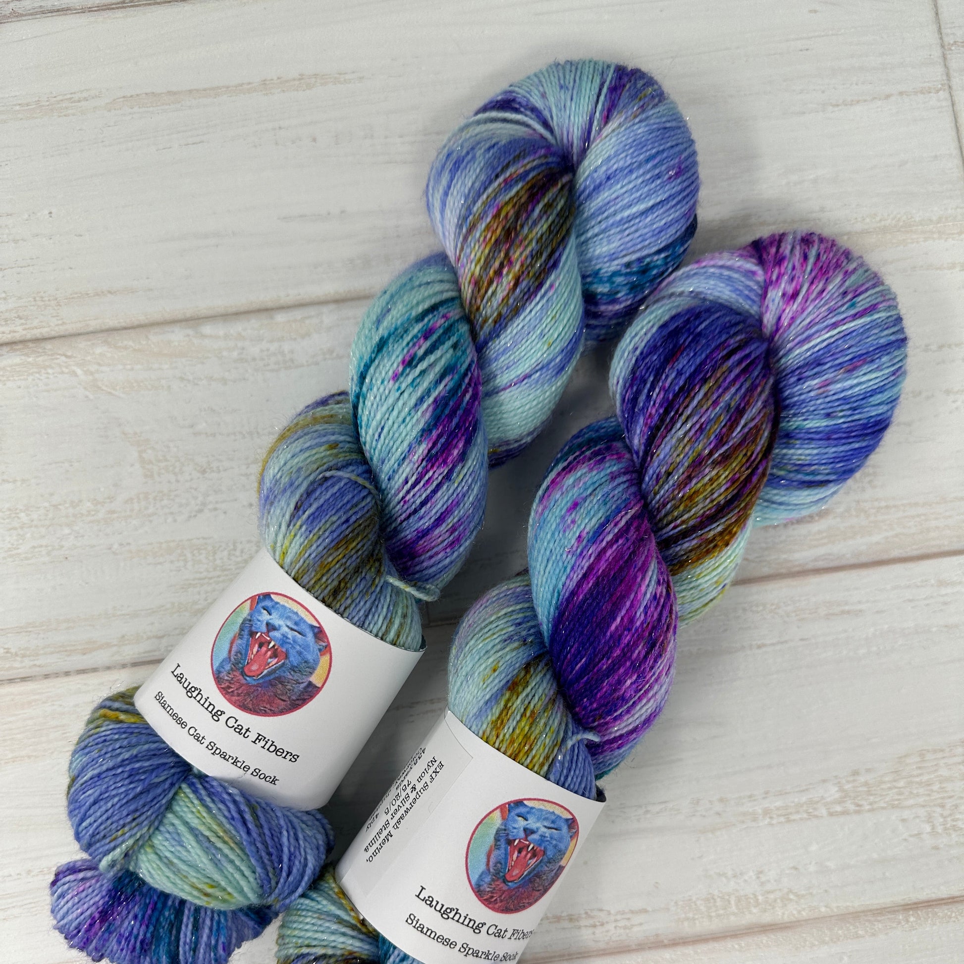 two skeins of hand dyed sparkle sock yarn by Laughing Cat Fibers in their Jupiter colorway 