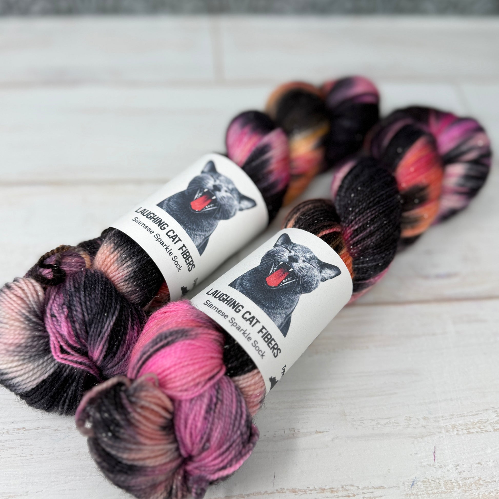 “Side angle of two skeins of The Poet X yarn highlighting the layered overdyed black glaze and subtle color depth.”