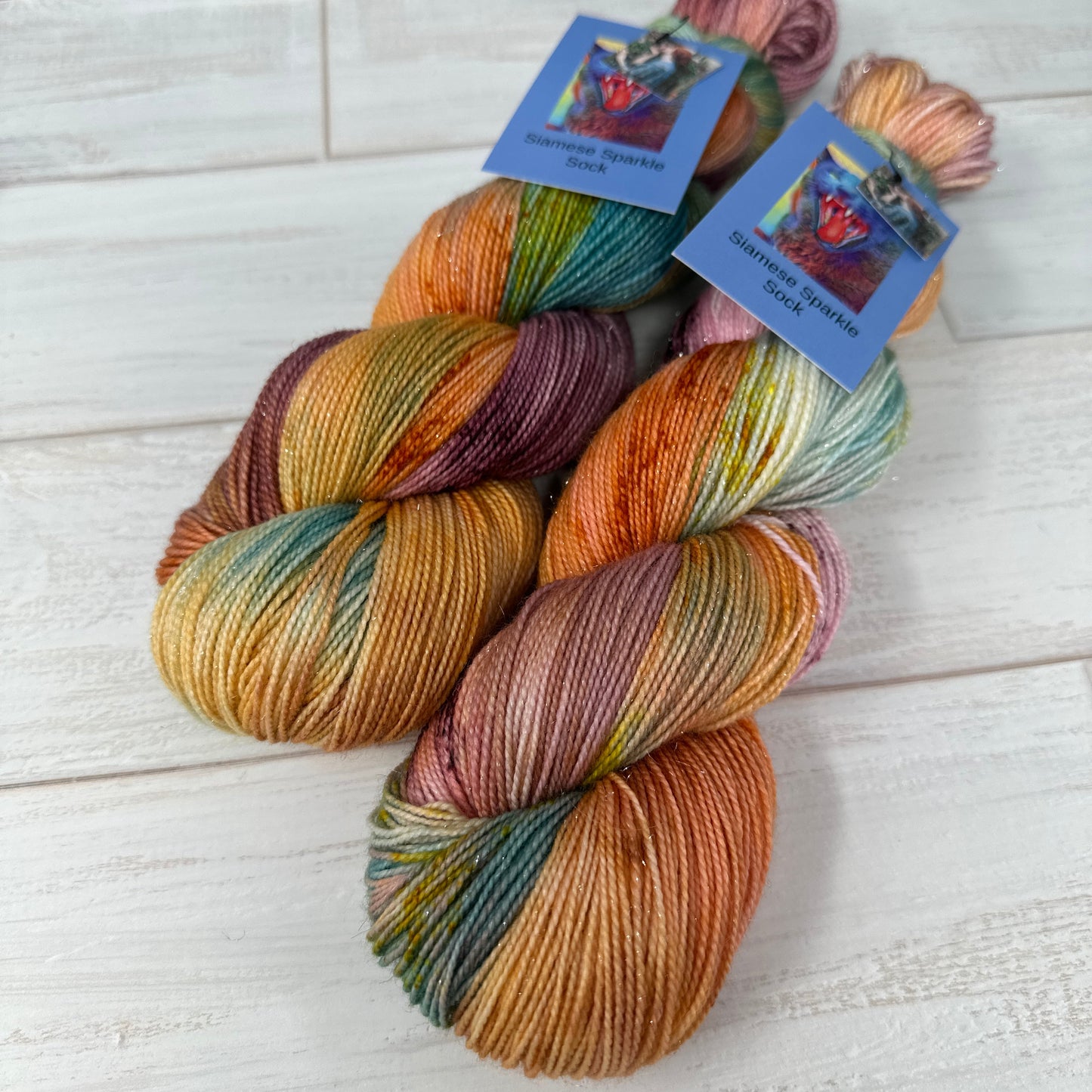 two skeins of hand dyed sparkle sock yarn by Laughing Cat Fibers dyed in their colorway The Soul of the Rose 