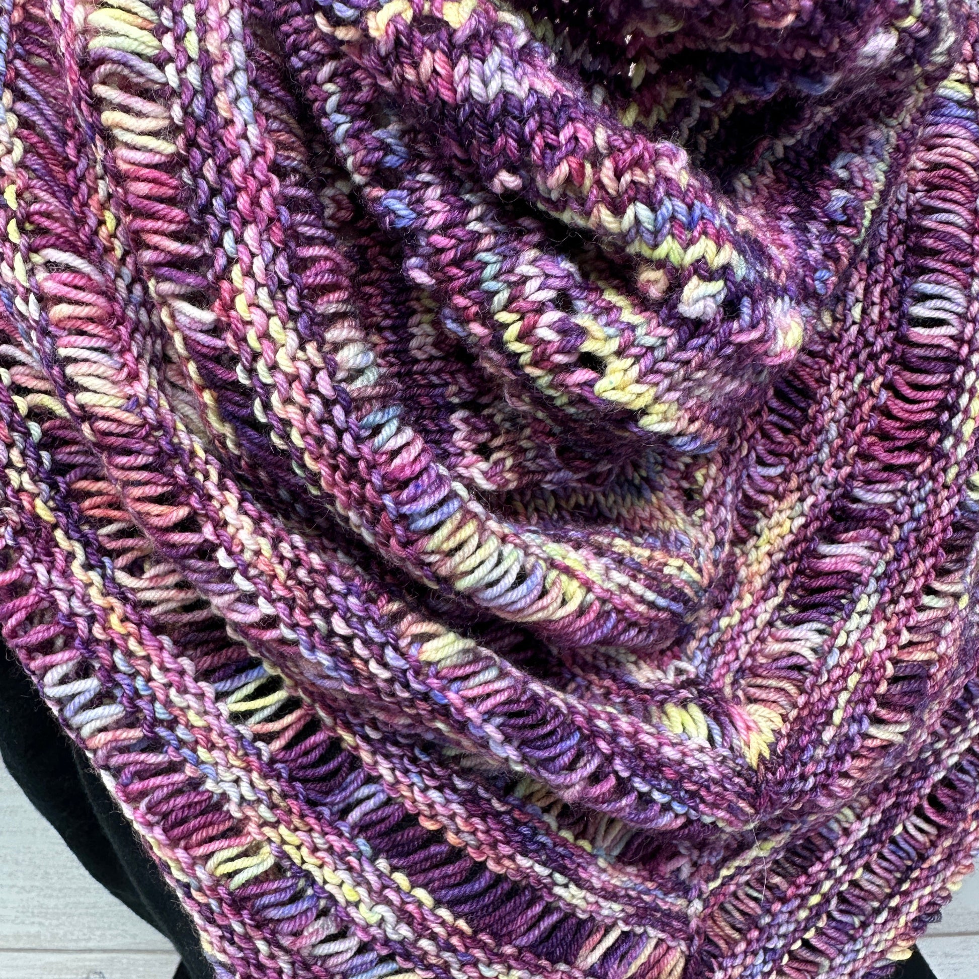Close-up of a knitted shawl with multicolor pattern on a wooden surface
