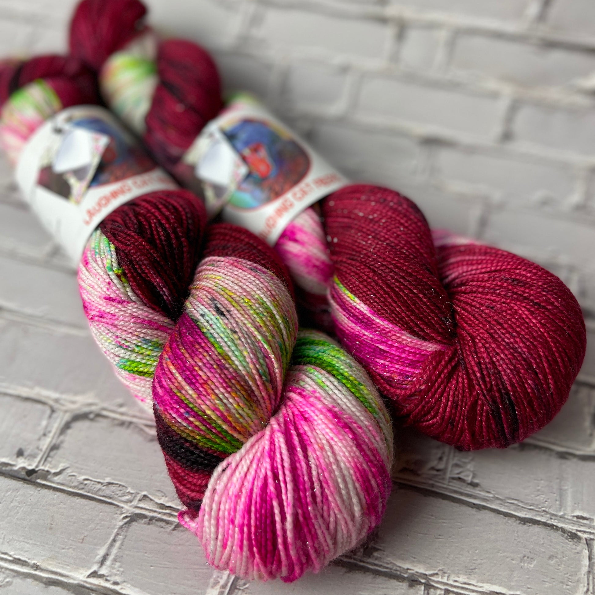Three skeins of multicolored hand dyed sparkle sock yarn by Laughing Cat Fibers dyed in the Offred colorway