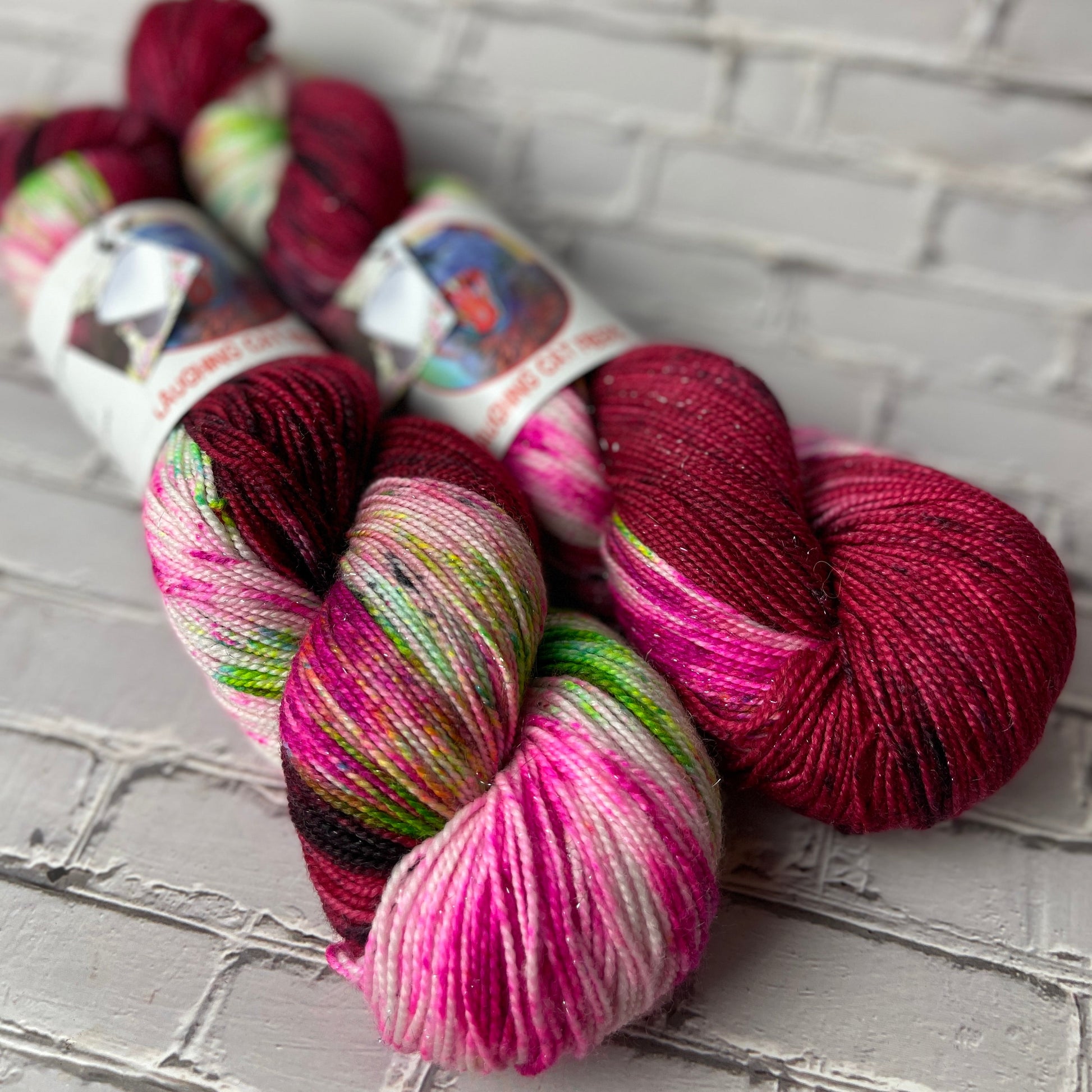 Three skeins of multicolored hand dyed yarn dyed by Laughing Cat Fibers dyed in the Offred colorway