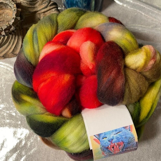 A bundle of colorful fiber roving with shades of red, green, and brown, dyed in the 'Tomato' colorway.
